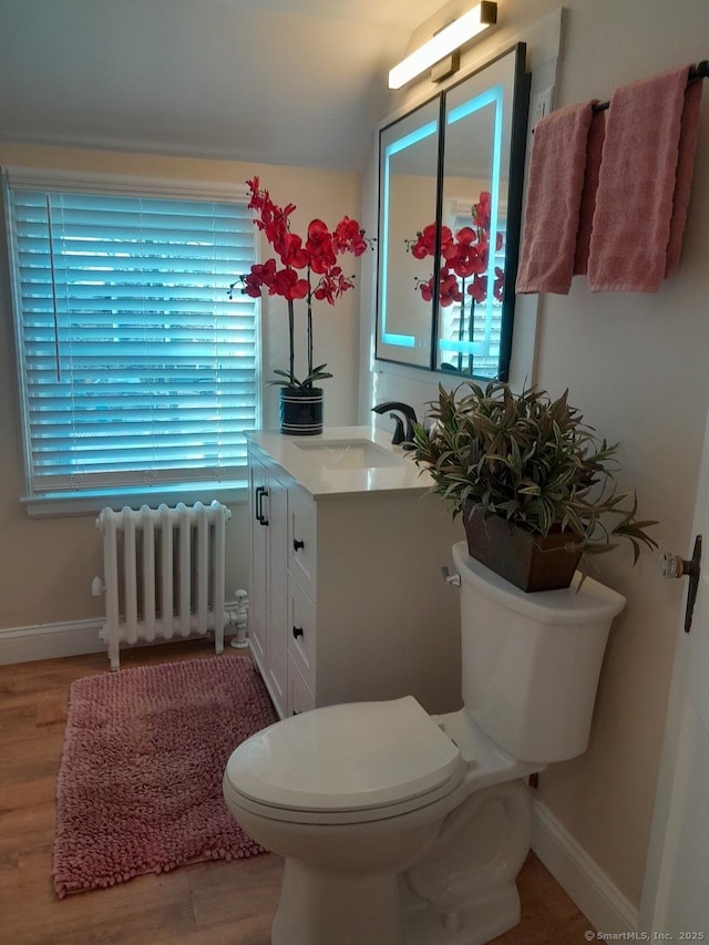 bathroom with radiator, hardwood / wood-style floors, vanity, and toilet