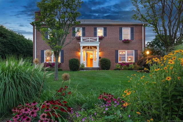 colonial inspired home featuring a lawn and a balcony