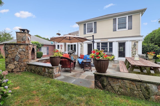 back of house with an outdoor living space with a fireplace, a yard, and a patio