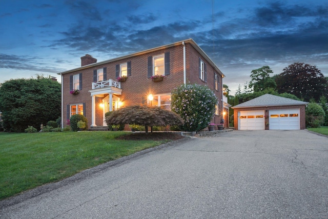 colonial home featuring a lawn, a balcony, an outdoor structure, and a garage