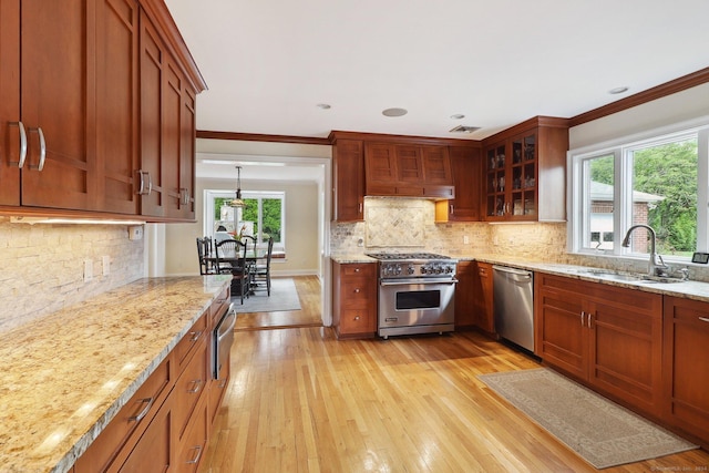 kitchen with light stone countertops, sink, light hardwood / wood-style flooring, and appliances with stainless steel finishes