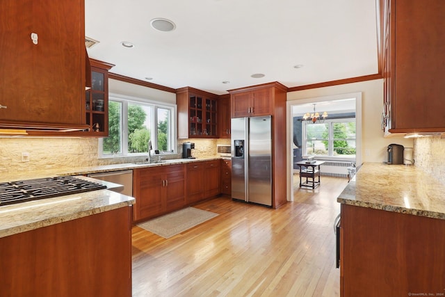 kitchen featuring backsplash, crown molding, stainless steel appliances, and light hardwood / wood-style floors