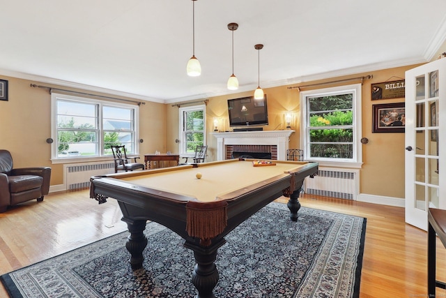 game room featuring light hardwood / wood-style flooring, a brick fireplace, radiator, and crown molding