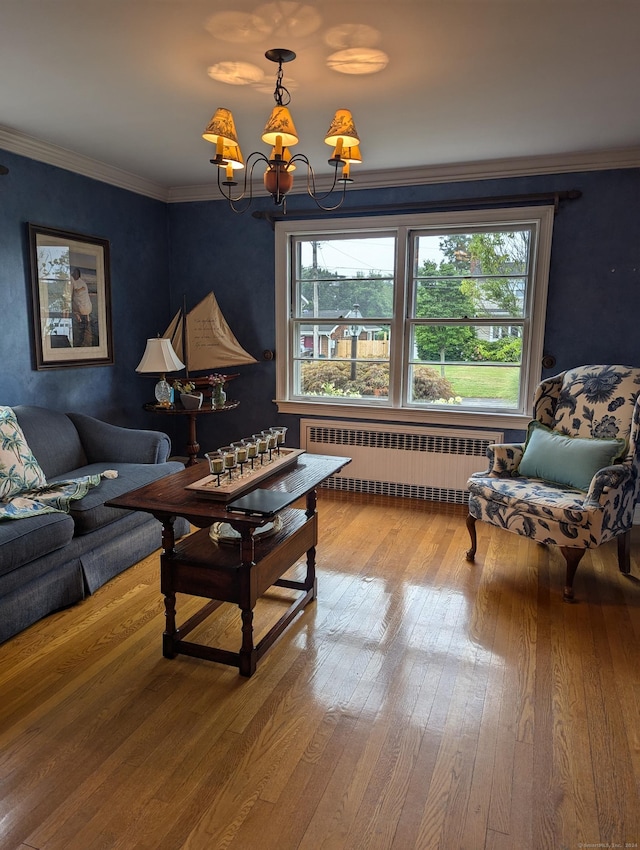 living room featuring hardwood / wood-style floors, a notable chandelier, radiator heating unit, and crown molding