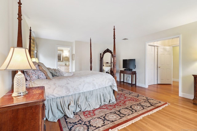 bedroom with wood-type flooring and ensuite bath