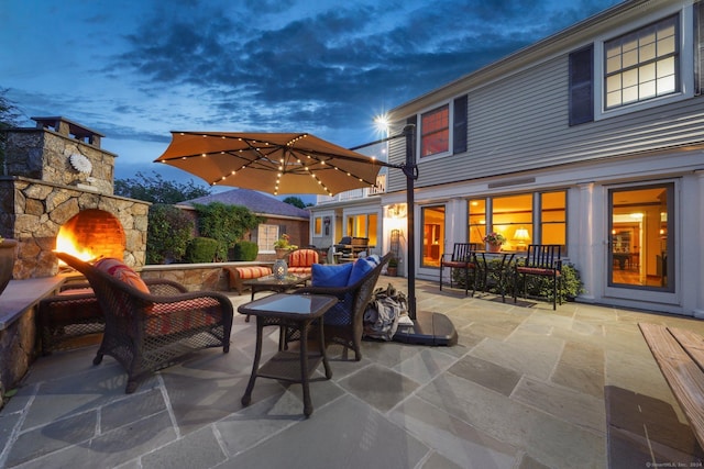 patio terrace at dusk featuring an outdoor living space with a fireplace