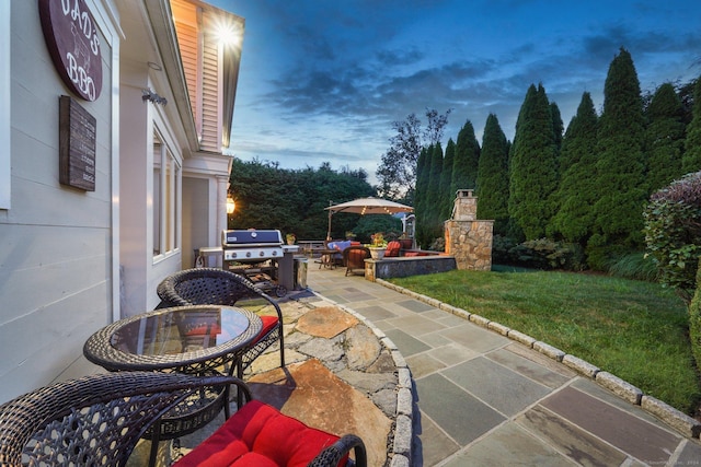 patio terrace at dusk with area for grilling and a yard