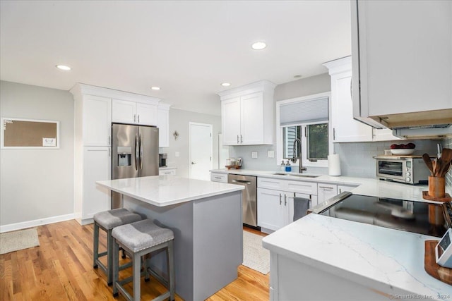 kitchen featuring a breakfast bar, tasteful backsplash, a kitchen island, white cabinetry, and stainless steel appliances