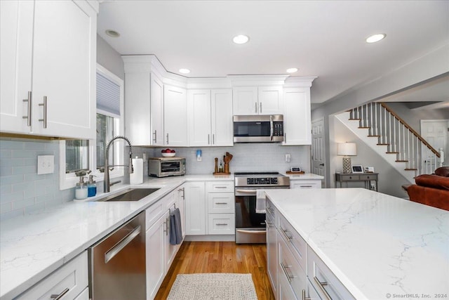 kitchen featuring sink, light stone countertops, tasteful backsplash, white cabinetry, and stainless steel appliances