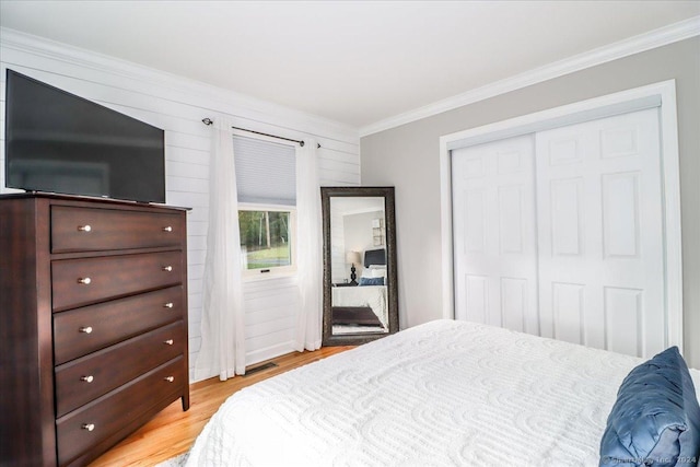 bedroom featuring light hardwood / wood-style floors, crown molding, and a closet