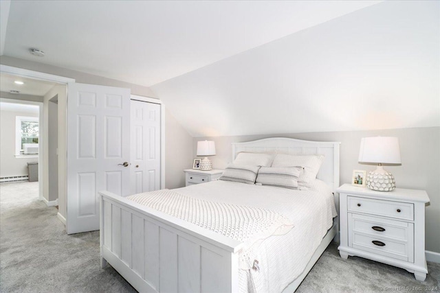 bedroom with a baseboard heating unit, light colored carpet, a closet, and lofted ceiling