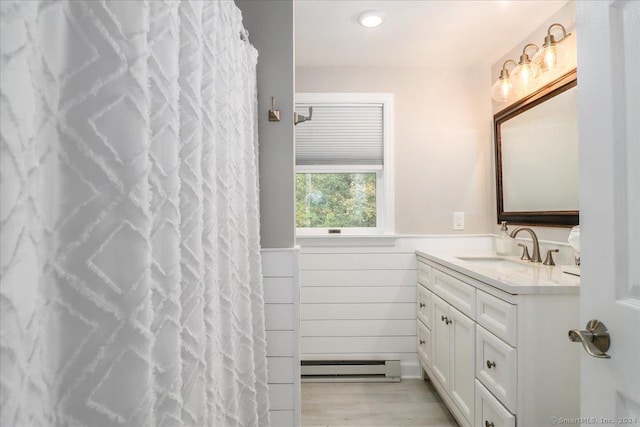 bathroom with walk in shower, vanity, and baseboard heating