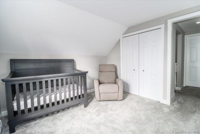 carpeted bedroom with vaulted ceiling, a closet, and a crib