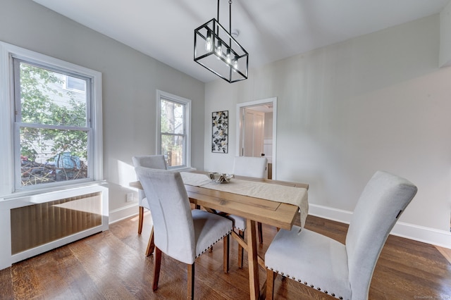 dining room with radiator, wood-type flooring, and a notable chandelier