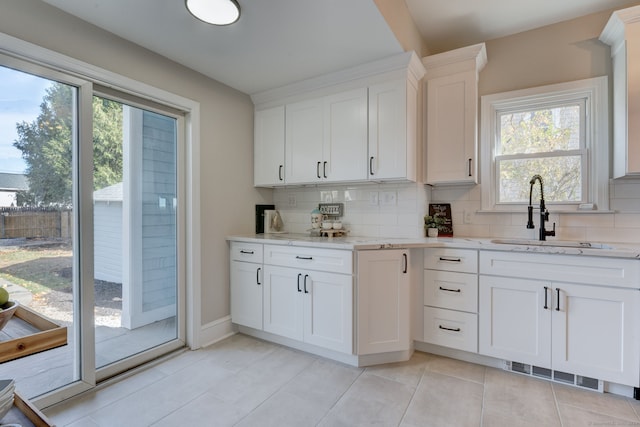 kitchen featuring tasteful backsplash, a wealth of natural light, white cabinetry, and sink