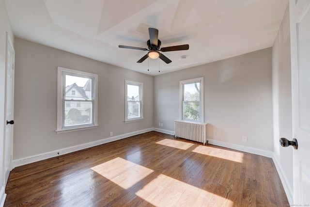 empty room with ceiling fan, dark hardwood / wood-style flooring, and radiator