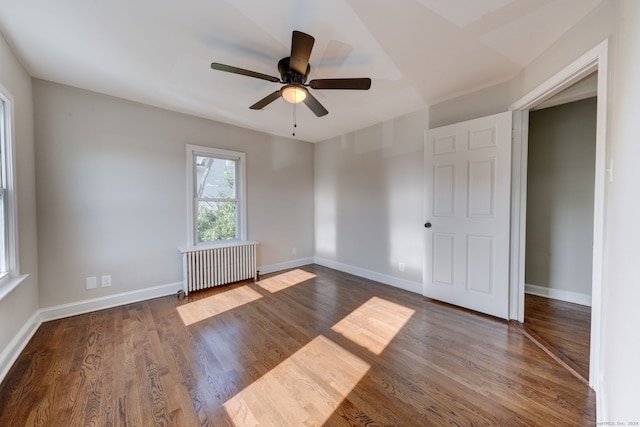 empty room featuring radiator, ceiling fan, and dark hardwood / wood-style flooring