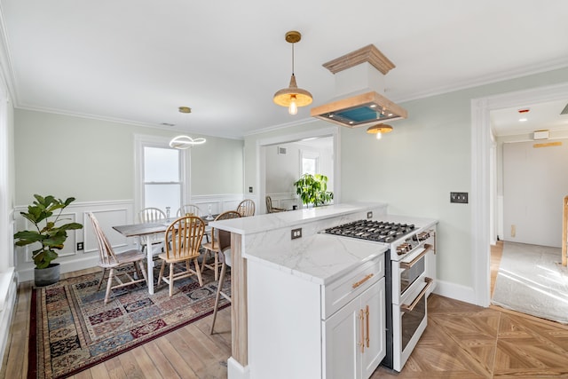 kitchen with range with two ovens, crown molding, hanging light fixtures, and white cabinets