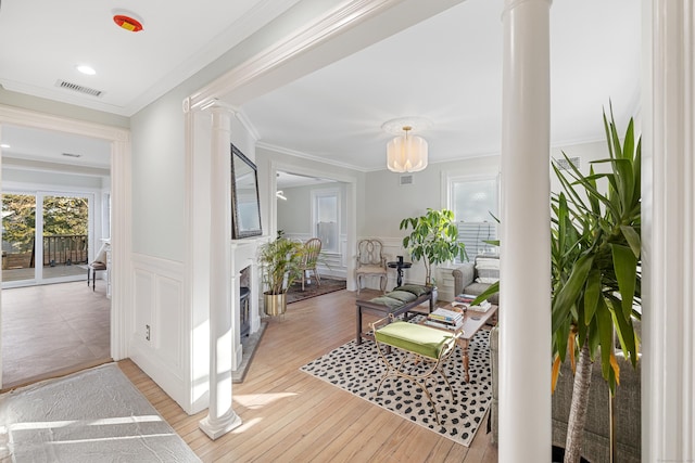 corridor featuring decorative columns, ornamental molding, and light wood-type flooring