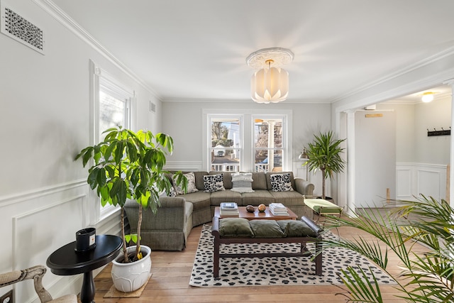 living room with crown molding, a wealth of natural light, and light wood-type flooring