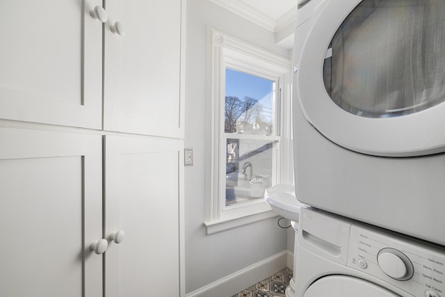 laundry room featuring crown molding and stacked washer / dryer