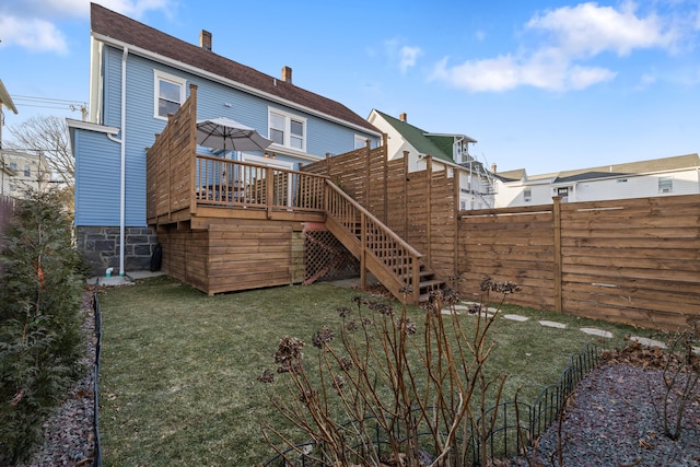 rear view of house featuring a wooden deck and a lawn