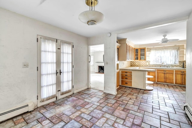 kitchen with sink, french doors, ceiling fan, decorative backsplash, and baseboard heating