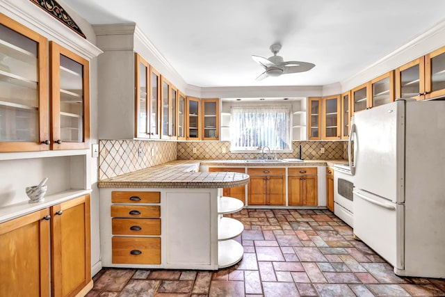 kitchen featuring white appliances, kitchen peninsula, ceiling fan, sink, and tasteful backsplash