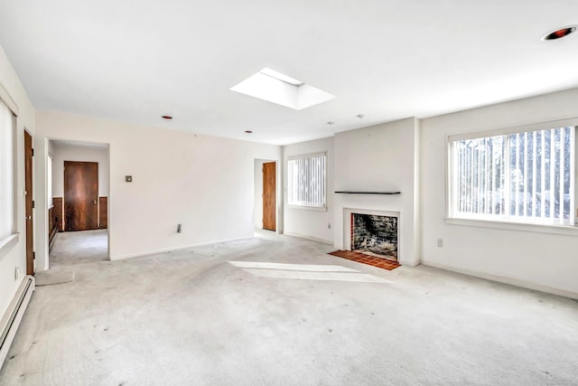 unfurnished living room with a healthy amount of sunlight, a skylight, light carpet, and a baseboard radiator