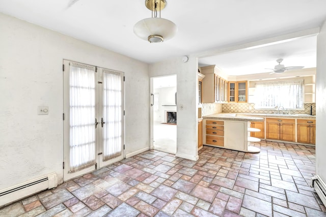 kitchen with french doors, decorative backsplash, a baseboard heating unit, ceiling fan, and sink