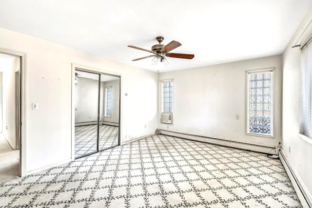 unfurnished bedroom featuring a baseboard heating unit, multiple windows, a closet, and ceiling fan