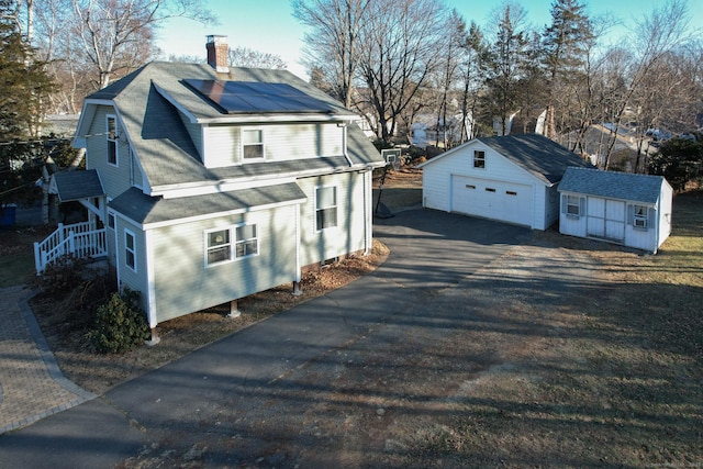 view of property exterior featuring solar panels, a storage unit, and a garage