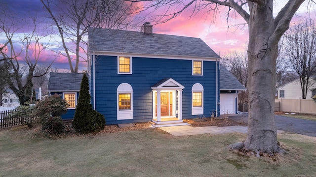 colonial home featuring a garage and a yard