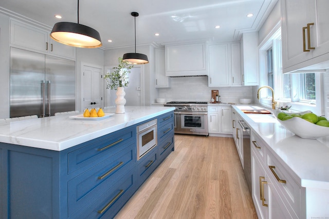 kitchen with blue cabinetry, white cabinetry, decorative light fixtures, and high end appliances