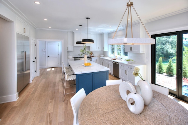 kitchen featuring tasteful backsplash, stainless steel appliances, a center island, white cabinetry, and hanging light fixtures