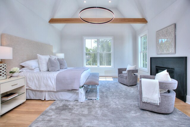 bedroom with vaulted ceiling with beams and light hardwood / wood-style floors