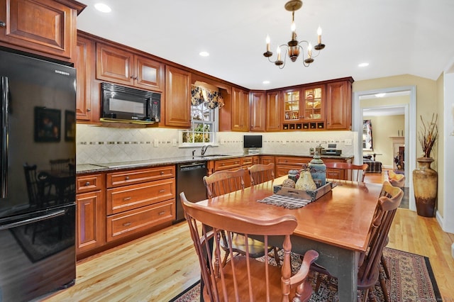 kitchen featuring an inviting chandelier, black appliances, sink, tasteful backsplash, and light hardwood / wood-style floors