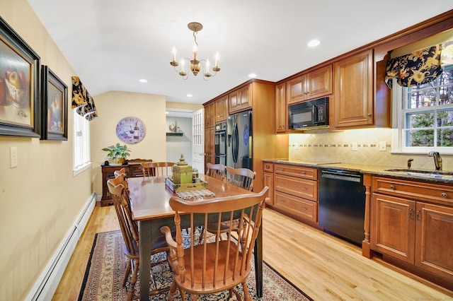 kitchen with dark stone counters, sink, black appliances, pendant lighting, and an inviting chandelier