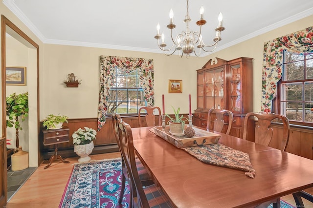 dining space with hardwood / wood-style flooring, wooden walls, an inviting chandelier, and ornamental molding