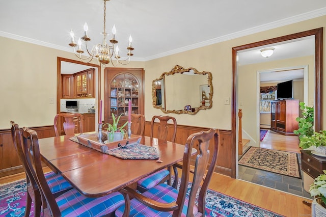 dining room with ornamental molding, light hardwood / wood-style flooring, and a notable chandelier