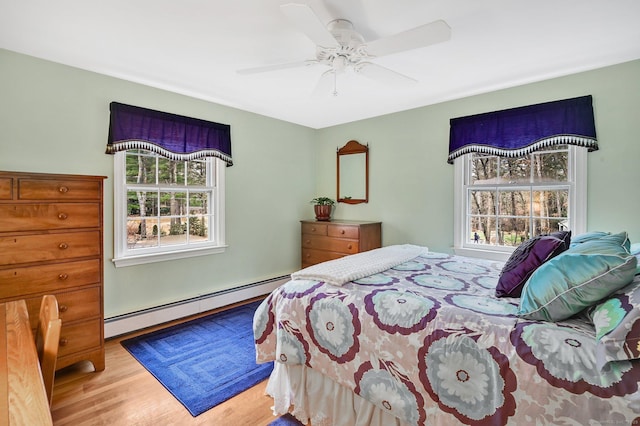 bedroom featuring light hardwood / wood-style floors, ceiling fan, and a baseboard heating unit