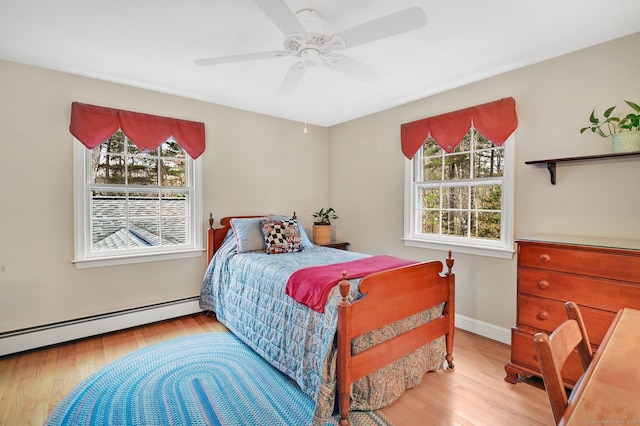 bedroom featuring ceiling fan, a baseboard heating unit, and light hardwood / wood-style flooring