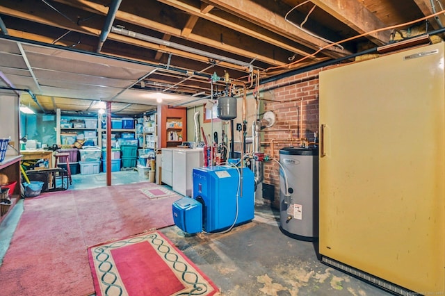 basement with electric water heater, washing machine and dryer, and brick wall