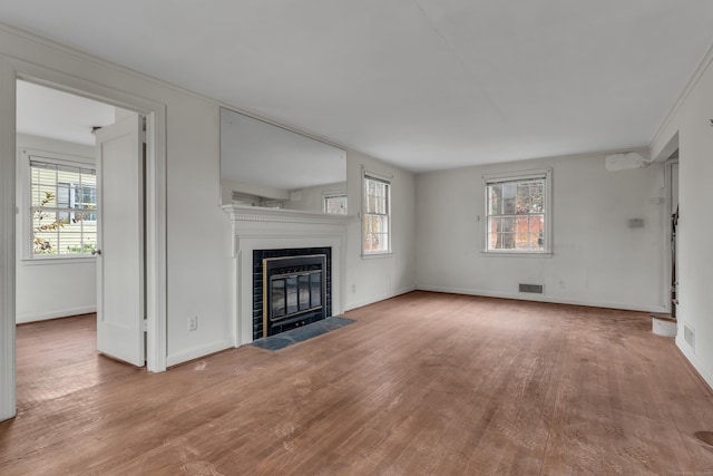 unfurnished living room with light hardwood / wood-style flooring and a tiled fireplace