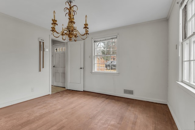 empty room with a chandelier, hardwood / wood-style floors, and crown molding