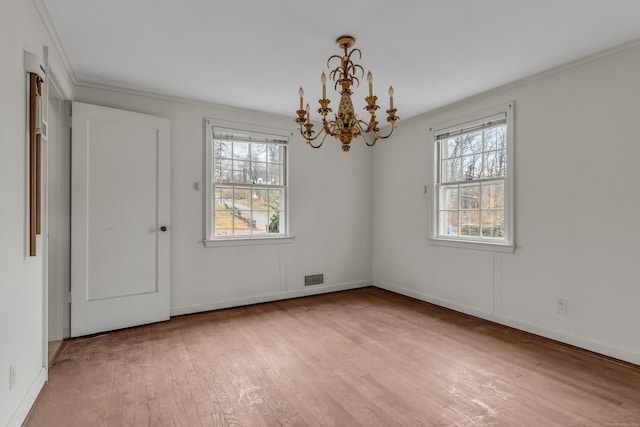 empty room with light wood-type flooring, crown molding, and a chandelier