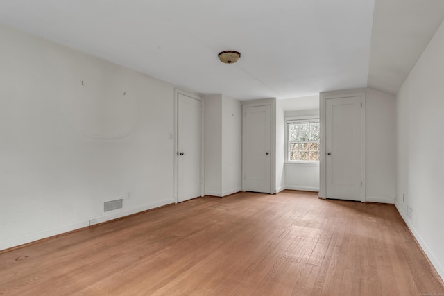 spare room featuring light hardwood / wood-style floors and lofted ceiling