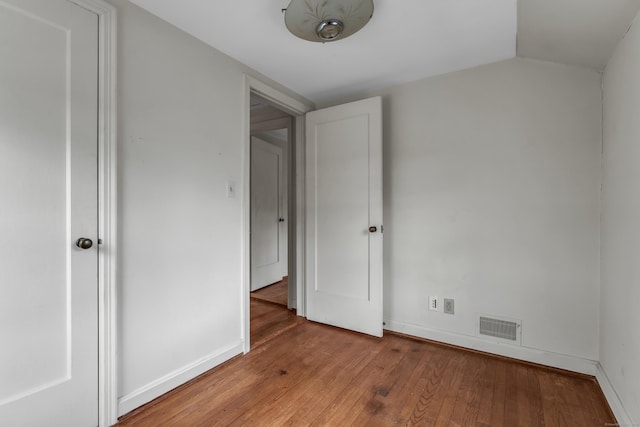 unfurnished bedroom featuring hardwood / wood-style floors and lofted ceiling