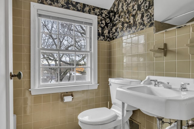 bathroom featuring toilet, sink, and tile walls