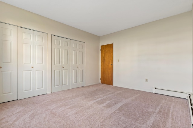 unfurnished bedroom featuring carpet flooring, two closets, and a baseboard heating unit